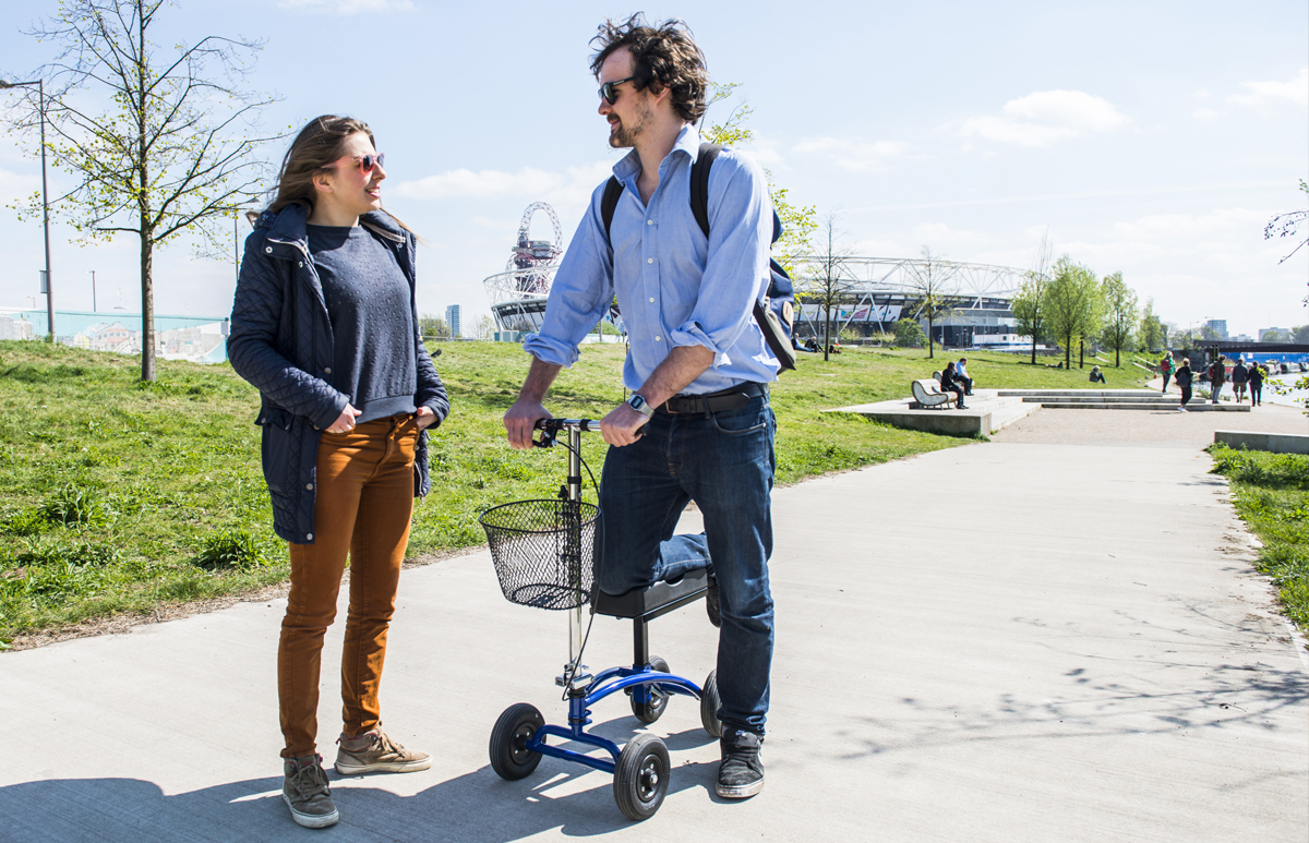 2 people chatting 1 on a knee scooter